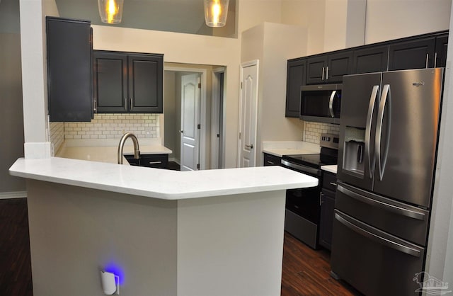1701 Eagle Ter, Cantonment, FL 32533 - kitchen featuring tasteful backsplash, stainless steel appliances, a peninsula, and dark wood-style floors