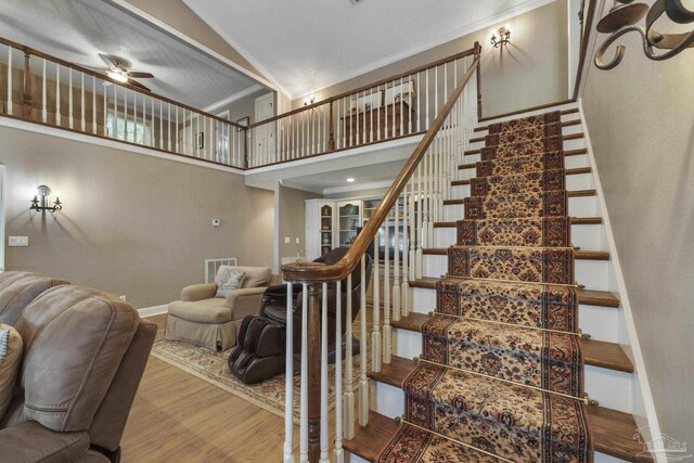 stairway featuring ceiling fan, high vaulted ceiling, ornamental molding, and hardwood / wood-style floors