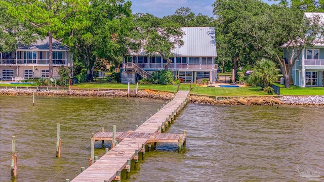 view of dock with a balcony, a water view, and a yard