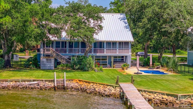 rear view of house with a patio, a sunroom, a water view, and a yard