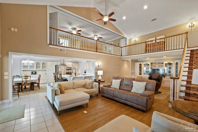 living room with ceiling fan, high vaulted ceiling, sink, and light wood-type flooring