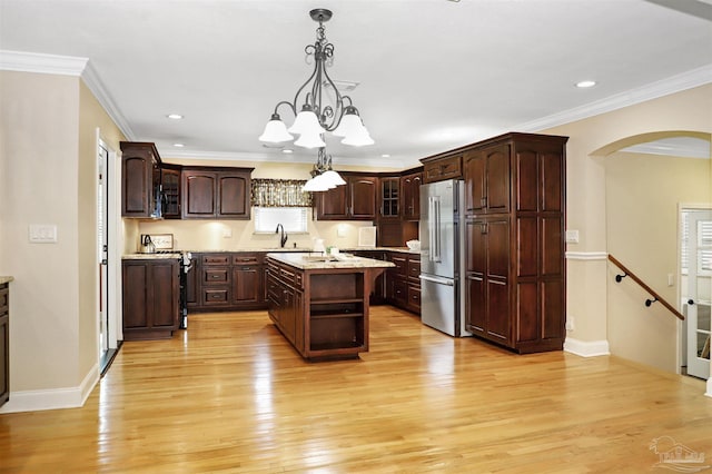 kitchen with hanging light fixtures, dark brown cabinets, a center island, high quality fridge, and light wood-type flooring