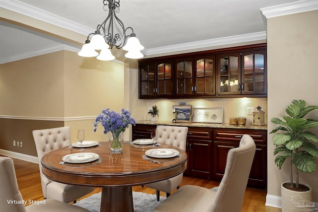 dining area with crown molding, hardwood / wood-style floors, and a chandelier