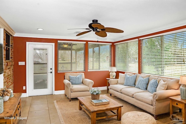 living room with crown molding, ceiling fan, a brick fireplace, and light tile patterned floors