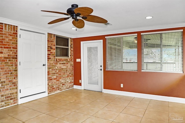 spare room featuring ornamental molding, brick wall, light tile patterned floors, and ceiling fan