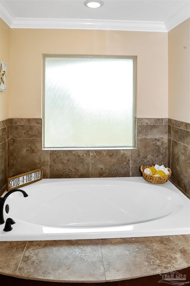 bathroom with crown molding, plenty of natural light, and a relaxing tiled tub