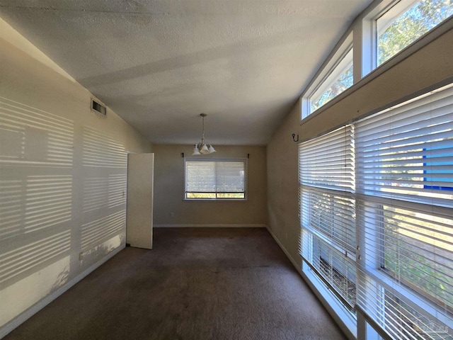 unfurnished room featuring a textured ceiling, a chandelier, vaulted ceiling, and dark carpet