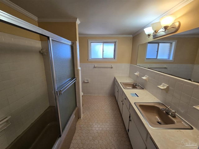 bathroom with tile patterned floors, bath / shower combo with glass door, vanity, crown molding, and tile walls