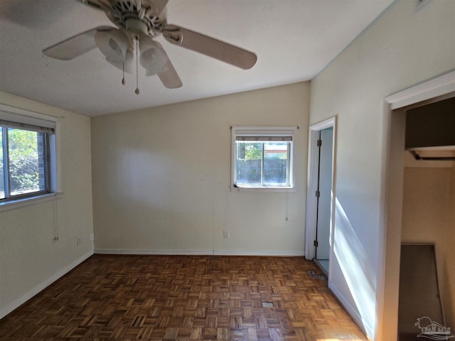 empty room with ceiling fan, a healthy amount of sunlight, dark parquet flooring, and vaulted ceiling