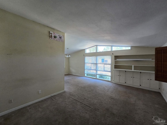 unfurnished living room with dark colored carpet, a textured ceiling, and vaulted ceiling