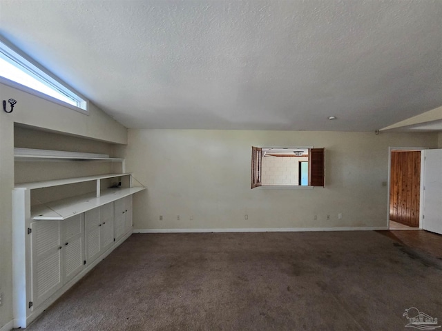 interior space featuring a textured ceiling, carpet floors, and vaulted ceiling