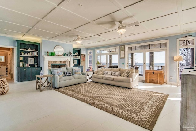 living room with built in shelves, french doors, a fireplace, ceiling fan, and coffered ceiling