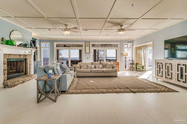 living room with a brick fireplace, coffered ceiling, ceiling fan, and light hardwood / wood-style floors