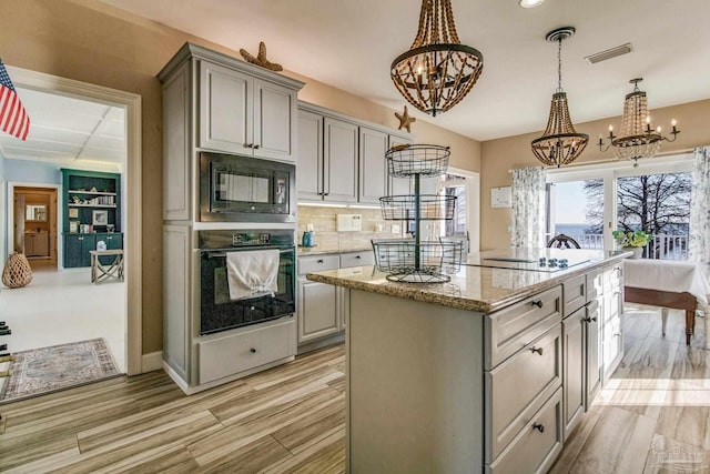 kitchen featuring black appliances, decorative light fixtures, a notable chandelier, and gray cabinetry