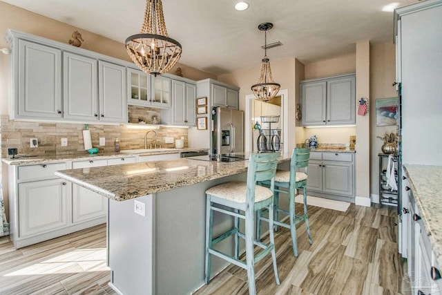 kitchen with sink, a center island, pendant lighting, and stainless steel fridge with ice dispenser