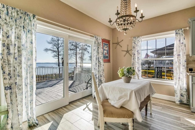 dining space with a notable chandelier, a water view, and light hardwood / wood-style floors