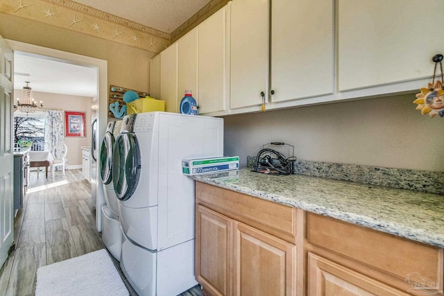 washroom with cabinets, washing machine and dryer, and a notable chandelier