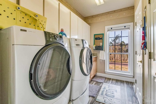 washroom featuring washing machine and dryer, light wood-type flooring, and cabinets