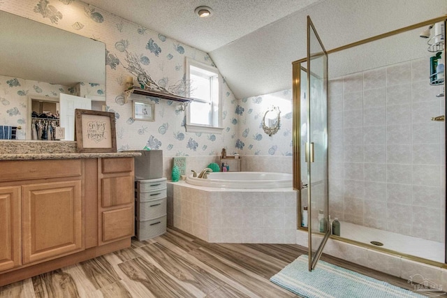 bathroom with independent shower and bath, hardwood / wood-style flooring, a textured ceiling, vanity, and lofted ceiling