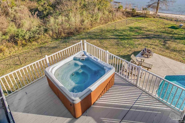 deck with an outdoor fire pit, a lawn, a water view, and a patio