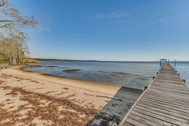 view of dock with a beach view and a water view