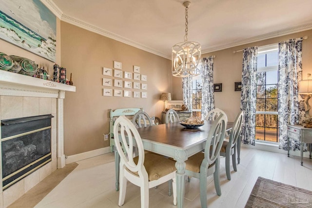 dining space featuring a tile fireplace, ornamental molding, and a chandelier