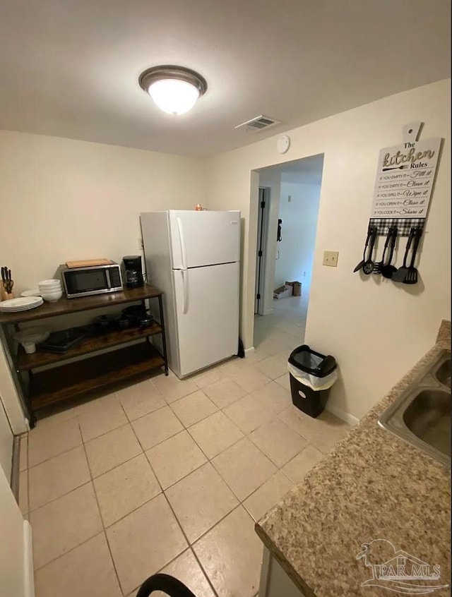 kitchen with white fridge, light tile patterned floors, and sink