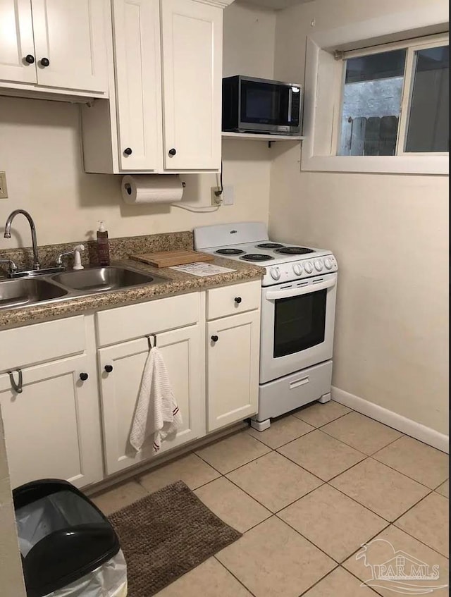 kitchen featuring white cabinets, light tile patterned flooring, sink, and white stove