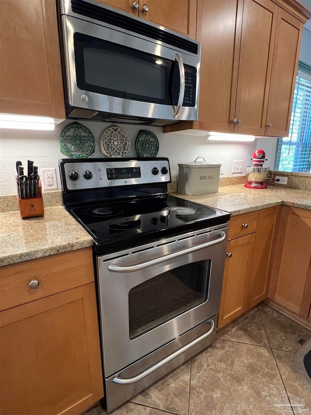 kitchen featuring light stone counters, stainless steel appliances, and light tile patterned floors