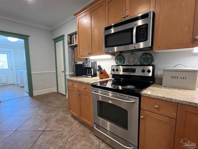 kitchen with ornamental molding, stainless steel appliances, light stone counters, and tile patterned flooring