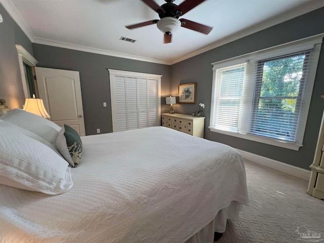 carpeted bedroom featuring crown molding, a closet, and ceiling fan