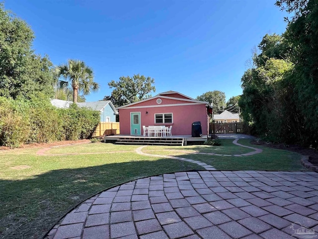 rear view of house featuring a deck, a patio, and a lawn