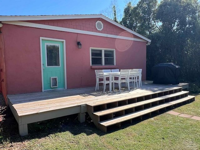 wooden deck featuring a yard and a grill