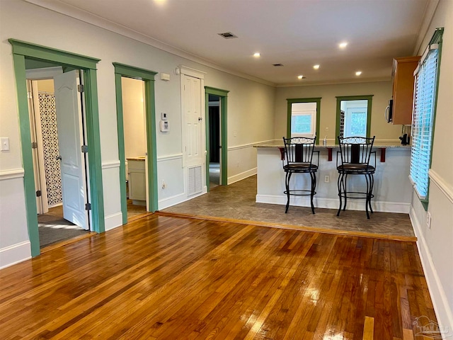 kitchen featuring a breakfast bar area, crown molding, kitchen peninsula, and dark hardwood / wood-style floors