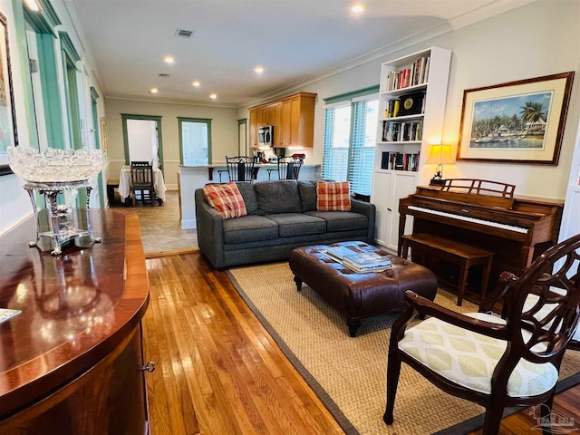 living room with ornamental molding and light hardwood / wood-style floors