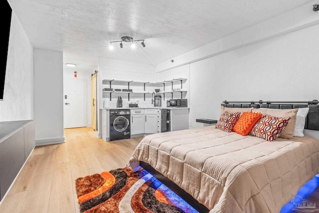 bedroom featuring washer / dryer, a textured ceiling, and light hardwood / wood-style floors