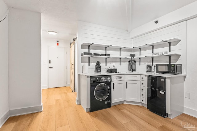 kitchen featuring white cabinetry, light hardwood / wood-style floors, black appliances, washer / dryer, and a barn door