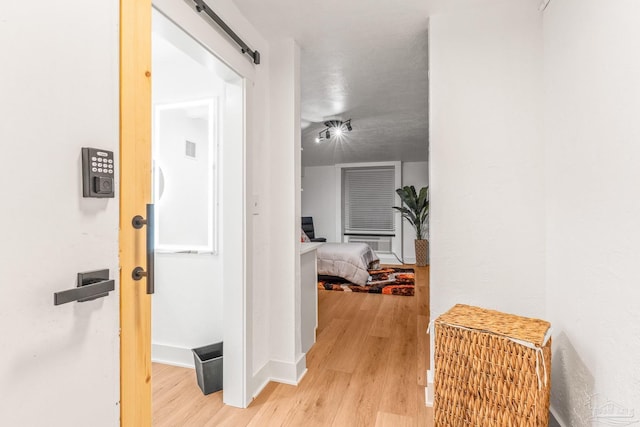 hallway with a barn door and light hardwood / wood-style flooring