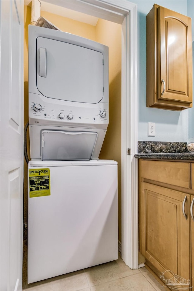 laundry room with stacked washing maching and dryer and light tile patterned floors