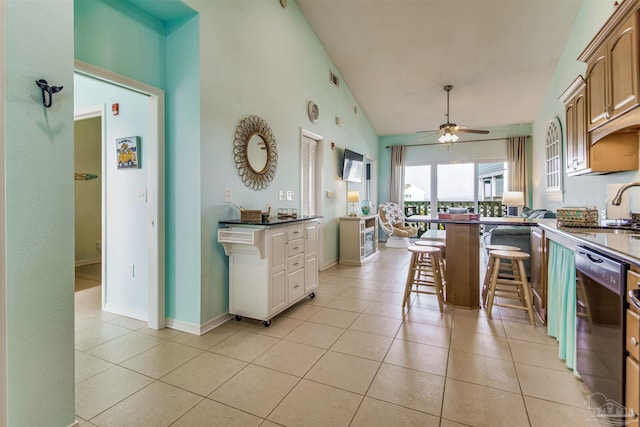 kitchen with a breakfast bar area, black dishwasher, sink, and light tile patterned floors