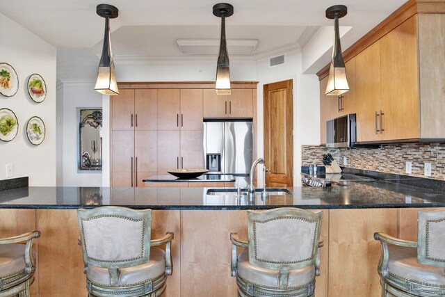 kitchen featuring kitchen peninsula, decorative backsplash, pendant lighting, stainless steel fridge, and sink