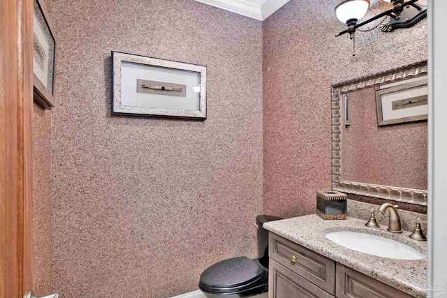 bathroom with toilet, vanity, and crown molding