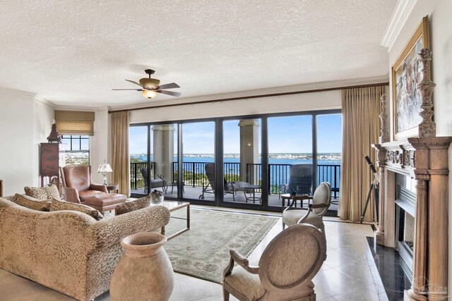 tiled living room featuring a water view, a textured ceiling, ceiling fan, and ornamental molding