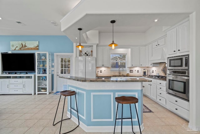 1669 Tidewater Ln, Navarre, FL 32566 - kitchen featuring appliances with stainless steel finishes, a breakfast bar, white cabinetry, and dark stone countertops