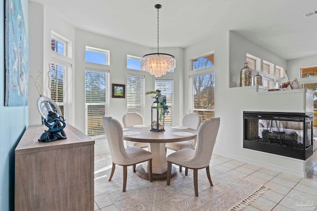 1669 Tidewater Ln, Navarre, FL 32566 - dining area featuring a chandelier, plenty of natural light, light tile patterned flooring, and a multi sided fireplace