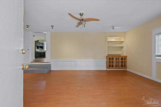 506 E Scott St, Pensacola, FL 32503 - unfurnished living room featuring built in features, a wainscoted wall, a ceiling fan, and wood finished floors