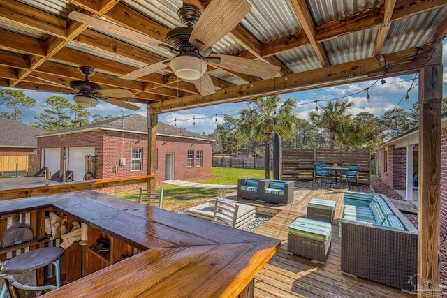 7770 Fenwick St, Navarre, FL 32566 - wooden terrace with an outdoor living space, a ceiling fan, outdoor dining area, an outdoor structure, and a garage