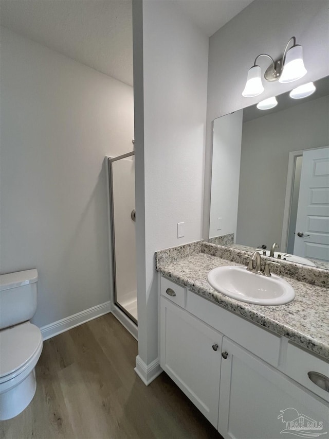 bathroom with hardwood / wood-style flooring, vanity, toilet, and an enclosed shower