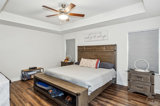 bedroom featuring ceiling fan, a tray ceiling, and dark hardwood / wood-style flooring