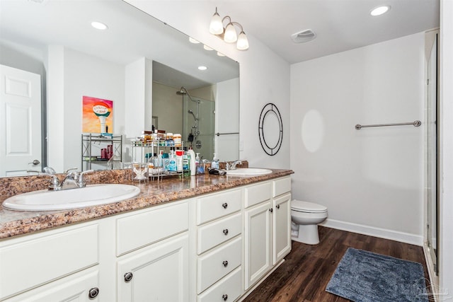 bathroom with toilet, vanity, a shower with door, and hardwood / wood-style floors